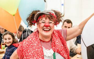 Eine Frau mit Zöpfen, die als Clown verkleidet ist und lacht