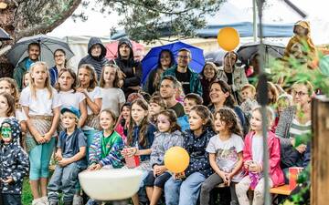 Eine große Gruppe von Kindern mit ein paar Erwachsenen, die staunend bei etwas zuschauen