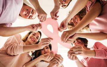 Sechs Frauen stehen im Kreis und halten gemeinsam die rosa Schleife, das Symbol gegen Brustkrebs