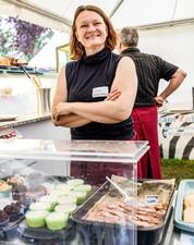 Frau freundlich lächelnd hinter einer Theke mit Essen
