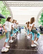 Eine Gruppe von Kindern in zwei Reihen auf einer Bühne, die einen Tanz aufführen